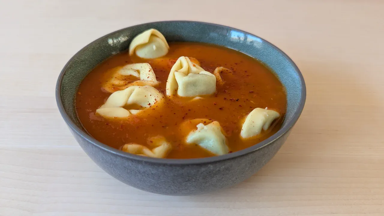 Cremige Tomaten-Tortellini-Suppe mit frischem Basilikum garniert.